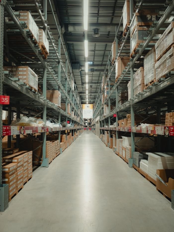 Spacious warehouse aisle with shelves filled with neatly stacked products and pallets.